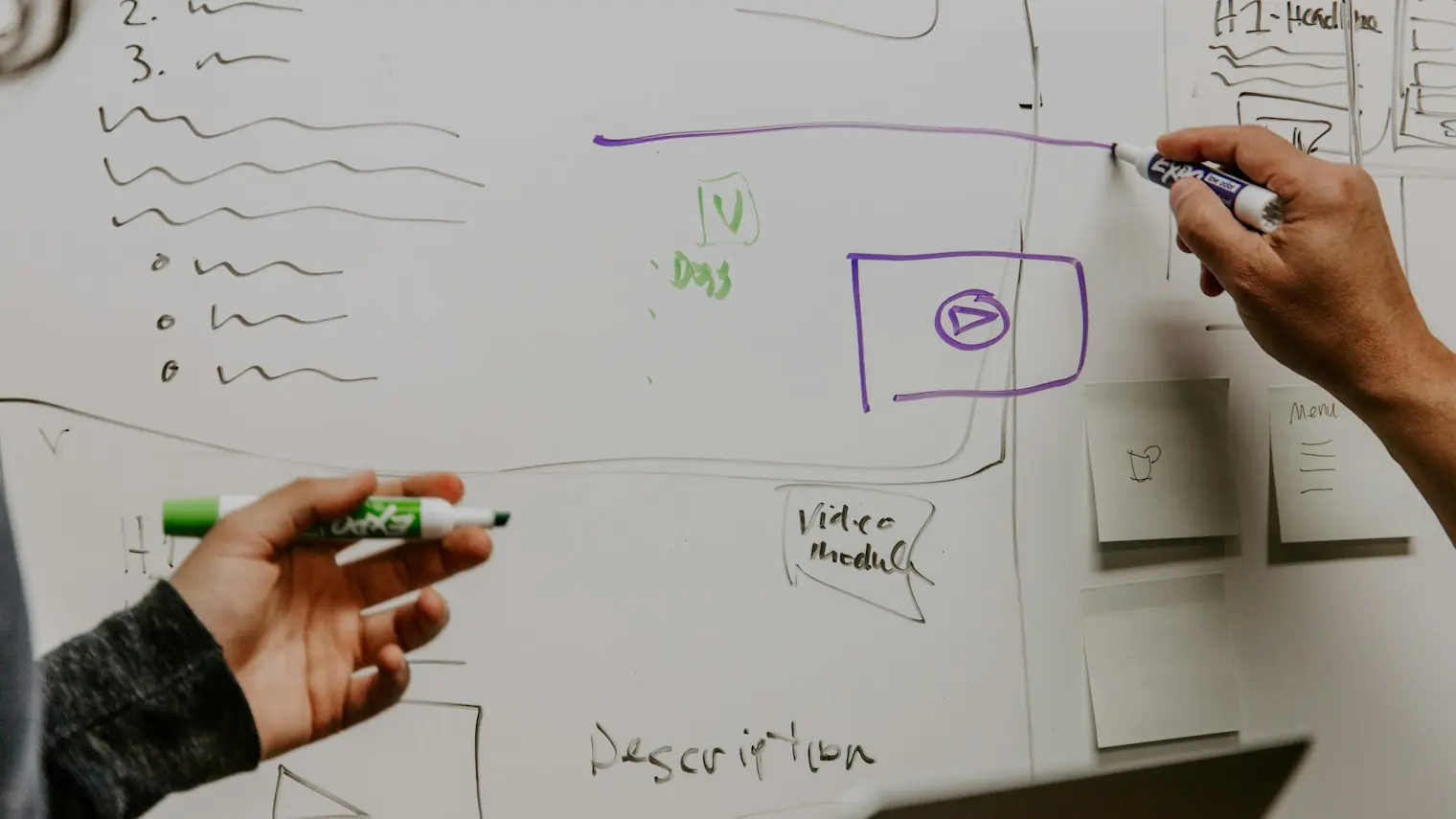 Two people sketching an idea on a whiteboard