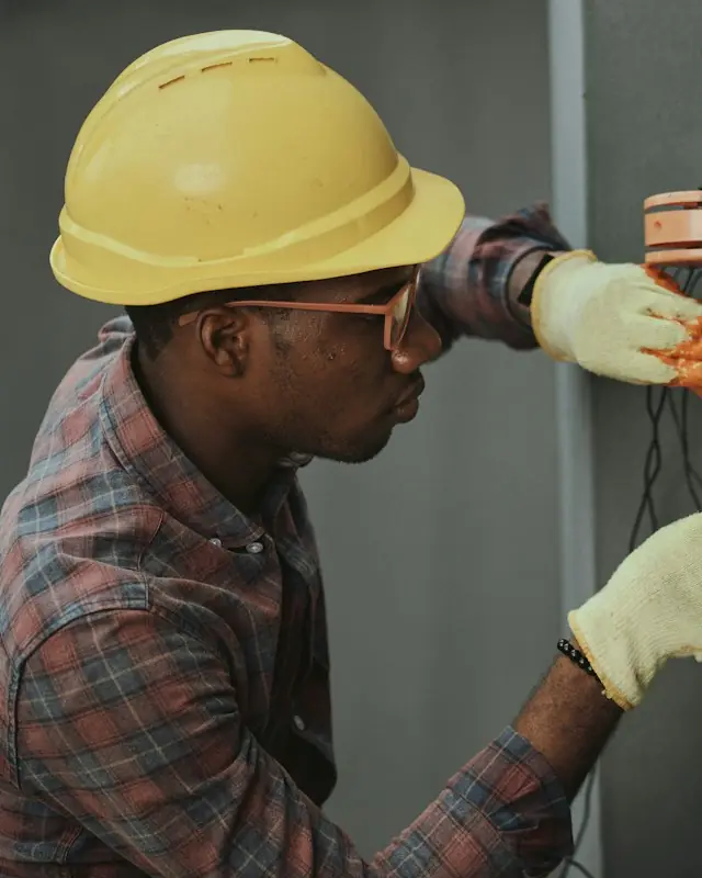 An electrician in a hard hat working on wiring